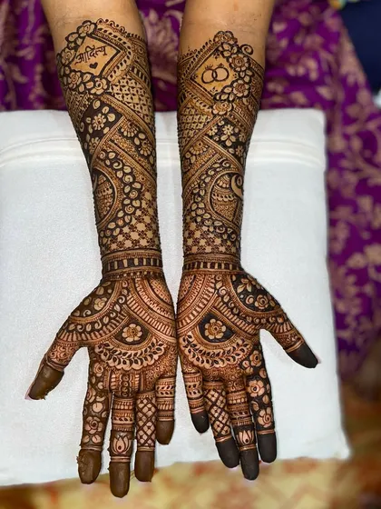 A beautiful design with the bride's name, 'Priya', and wedding rings incorporated into a traditional pattern with peacocks and flowers.