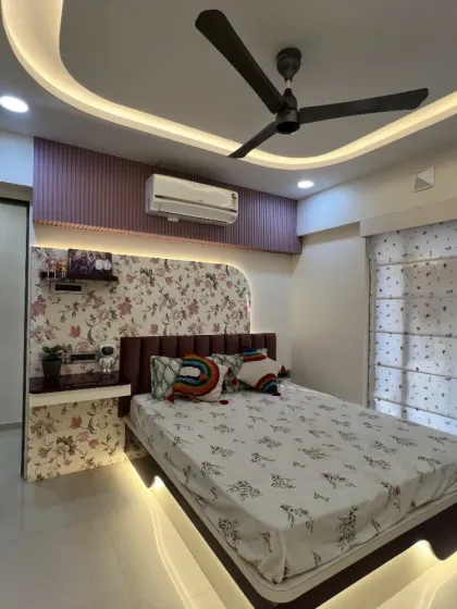This bedroom combines floral wallpaper with a rainbow cushion and under-bed lighting, creating a cheerful and dreamy space.