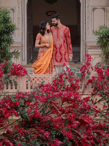 A romantic portrait of the couple against a backdrop of vibrant red bougainvillea. The decor becomes a part of their love story.