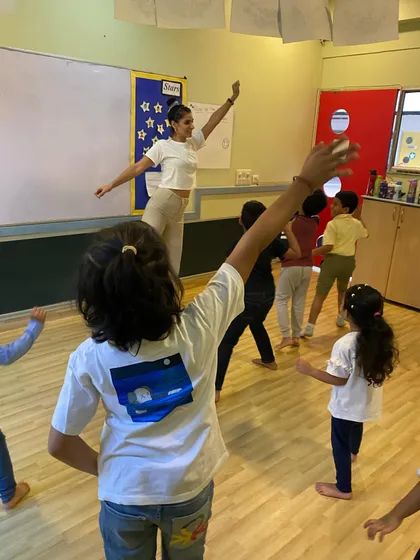 Leading the children in a mirroring exercise. This activity builds focus, observation skills, and physical coordination.