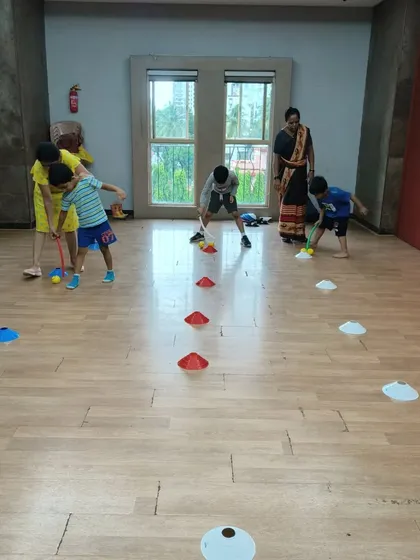 Rain can't stop our fun! When we move indoors, we switch to different games that keep the energy high. Here, we're working on hand-eye coordination with a fun hockey-style drill, learning to control the ball and aim for the target.