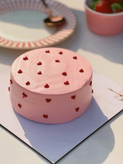 Simple, sweet, and full of love. This pink mini cake is decorated with tiny red hearts, making it a perfect treat for Valentine's Day or an anniversary.