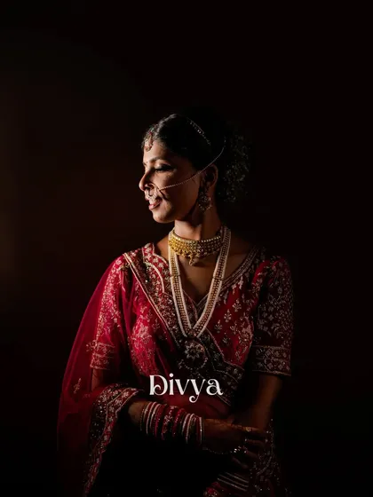 A classic, moody portrait of the bride, Divya. The dark background and soft lighting create a timeless and elegant image that focuses entirely on her.