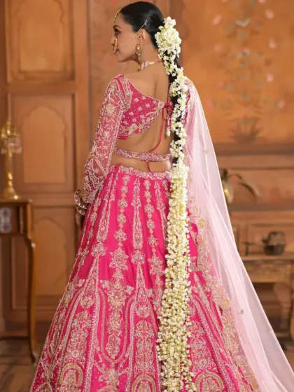 A full back view of an exceptionally long gajra braid for a bridal couture shoot. The hairstyle is designed to be dramatic and opulent, matching the heavily embroidered pink lehenga.