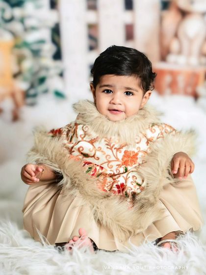 Dressed in a beautiful embroidered poncho with fur trim, this baby is ready for her winter-themed session. The soft, snowy set creates a cozy and festive atmosphere.