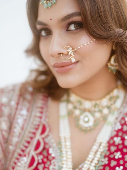 A close-up portrait that captures the bride's serene beauty. The makeup is focused on creating a luminous glow, with a neutral lip color to balance the look.