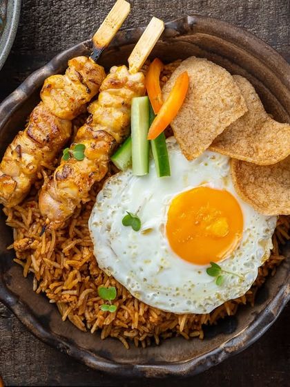 Nasi Goreng, an Indonesian fried rice dish with chicken satay and a fried egg, from the YouMee archives.