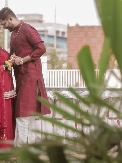 An intimate forehead-to-forehead pose on a city rooftop. The blurred foreground plant adds a creative touch, making the moment feel more private.