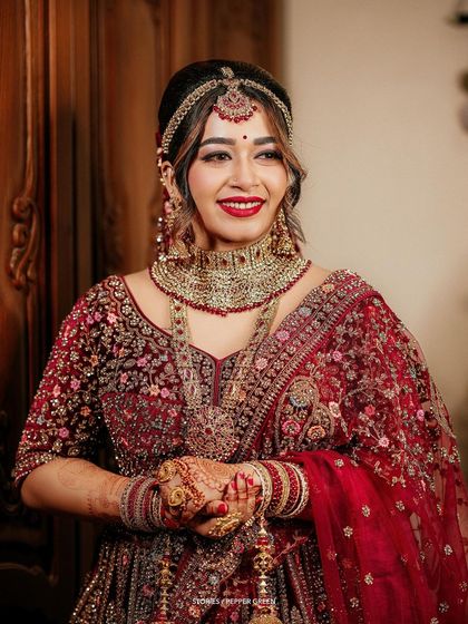 A joyful portrait of the bride, Reshma, in her stunning red and gold lehenga. Her happy expression and beautiful attire make for a perfect bridal shot.