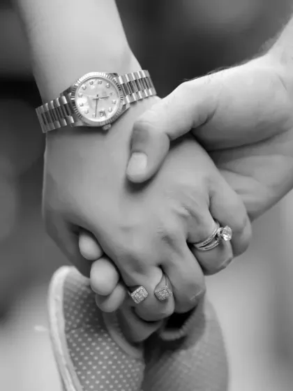 This black and white shot focuses on the details, showing a parent's hands gently holding their baby's tiny feet. It's a symbolic photo of protection and love.