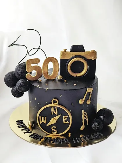 A cake for a 50-year-old who loves travel, photography, and music. This black and gold cake combines all his passions into one stylish design.
