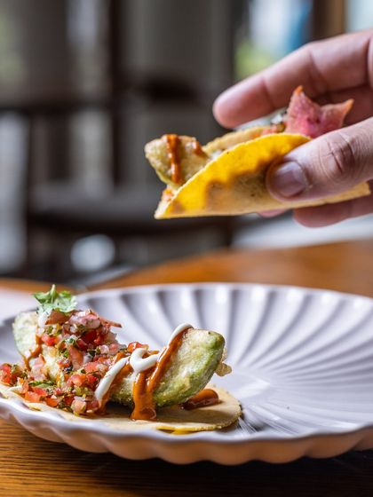 One bite and you’ll be taco-ing ‘bout it for days. A hand holds up a mini Avocado Taco, ready to be enjoyed.