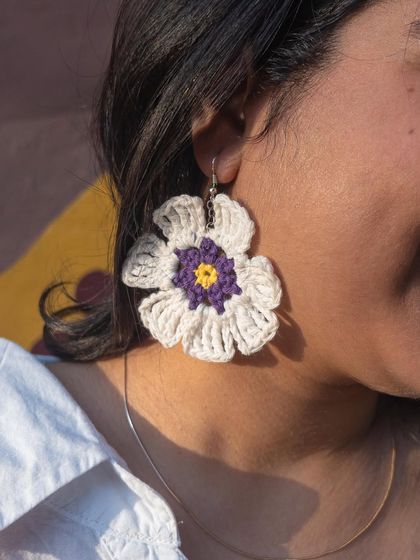 A model showing off the scale and beauty of the large floral crochet earrings. They are designed to be a centerpiece accessory, handmade with intricate detail.