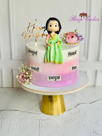 A cake as graceful as she is. This custom birthday cake celebrates the many virtues of a wonderful woman, topped with a fondant figurine in a green saree.