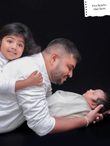 A father and daughter share a sweet moment with the family's newborn. This pose beautifully illustrates the love and protection within the family.