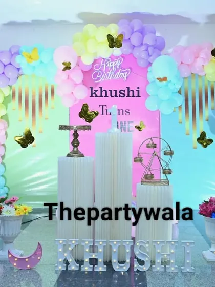A dreamy butterfly theme with a pastel rainbow balloon arch and a pink backdrop. The golden butterfly stickers add a touch of sparkle to the whole setup.
