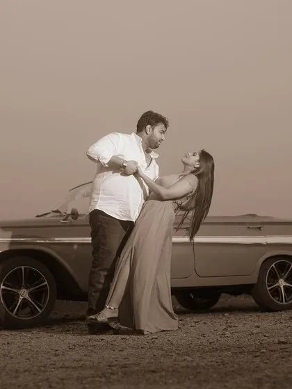 A sepia-toned version of the couple's dance by the vintage car, adding a timeless and classic feel to the pre-wedding photo.