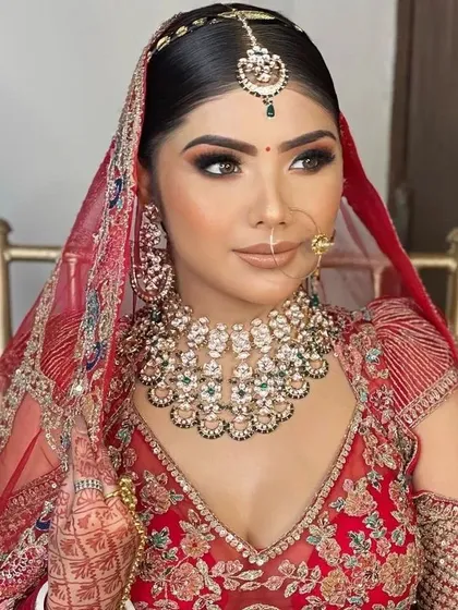 A close-up of one of our happy clients in a classic red bridal lehenga. The intricate embroidery is perfectly complemented by the green and white stone Kundan jewellery set she rented from us.