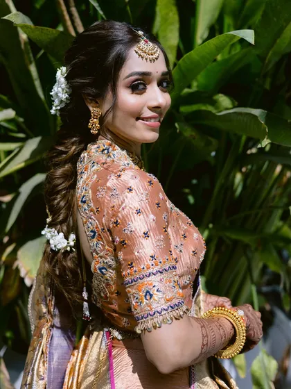 A beautiful side profile showing the intricate braided hairstyle with fresh flowers, a hallmark of South Indian bridal beauty.