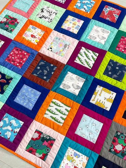 A vibrant baby quilt with a "square in a square" pattern, using many different fun and colorful prints.