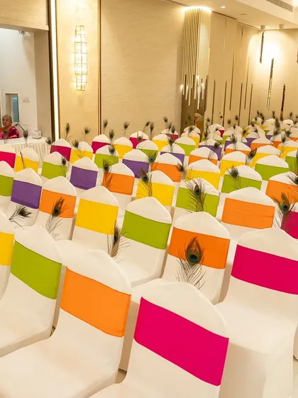 To ensure a cohesive look, even the seating for the Garba night was themed. Chairs were adorned with multi-colored sashes and peacock feathers, tying into the vibrant Radha-Krishna color palette of the event.