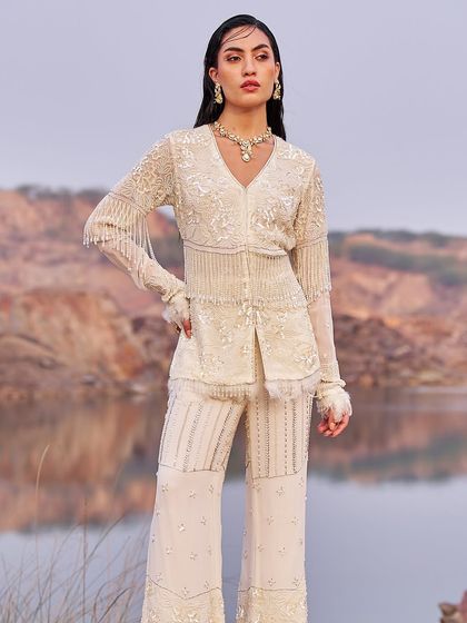 A stunning ivory co-ord set with intricate beadwork and fringe details. The tailored jacket and flared pants create a powerful, modern look for a cocktail party or reception.