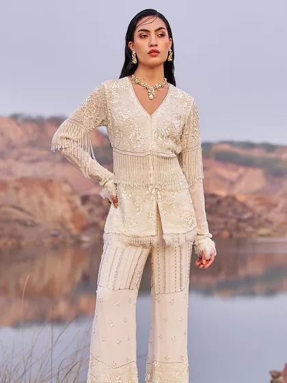 A stunning ivory co-ord set with intricate beadwork and fringe details. The tailored jacket and flared pants create a powerful, modern look for a cocktail party or reception.