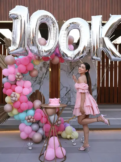 A full-length shot showing how the entire decor setup, including the balloon arch and '100K' foil balloons, came together for this special influencer milestone party.