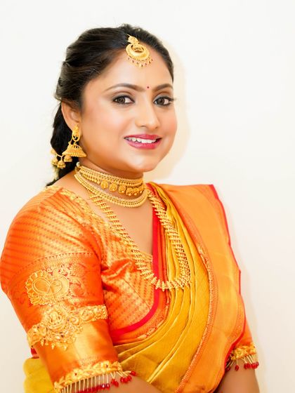 A bright and beautiful portrait. The bride's makeup is fresh and radiant, with a classic red lip that stands out against the golden tones of her saree.