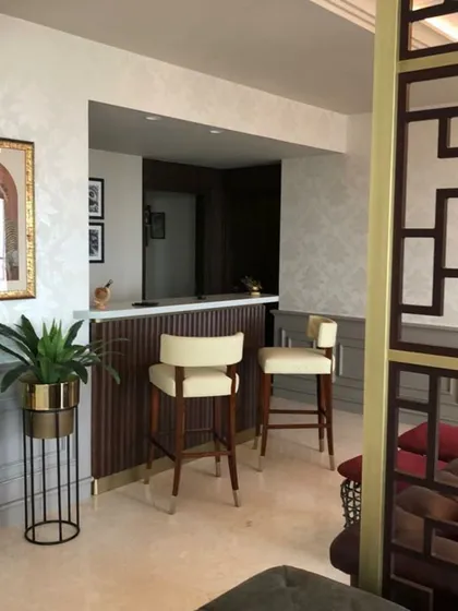We integrated a compact and stylish home bar into this residence. The design features fluted wood paneling and a marble countertop, complemented by elegant bar stools to create a dedicated space for entertaining.
