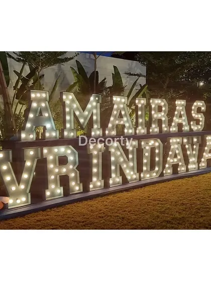 Large, illuminated marquee letters spelling out "AMAIRA'S VRINDAVAN," creating a spectacular entrance at night.