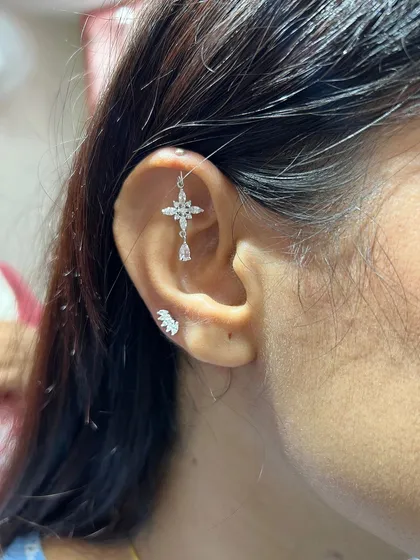 A cross-shaped hanging adds a touch of faith and fashion to this ear, balanced by a simple, sparkling wing stud on the tragus.