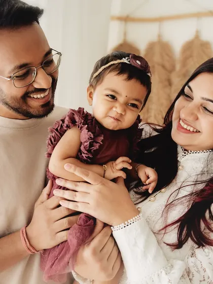 The joy is contagious in this family photo. The parents' happy expressions as they hold their daughter reflect a year full of love and wonderful memories.