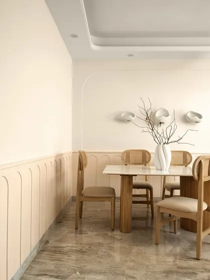 This view of the dining room shows the soft, curved paneling on the lower half of the wall, adding a subtle architectural detail. The space is designed for slow, intentional dinners with family.