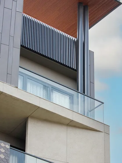 A detail of the balcony on the Akashneem Marg project, showing the clean lines of the glass railing and the contrast between the smooth concrete and the textured ceiling.