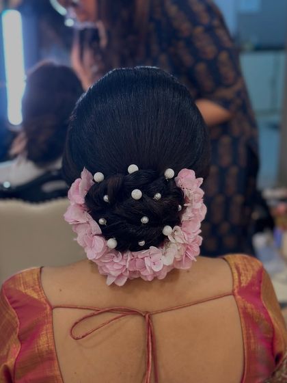 A close-up shot that details the placement of the flowers and pearls on the twisted bun.