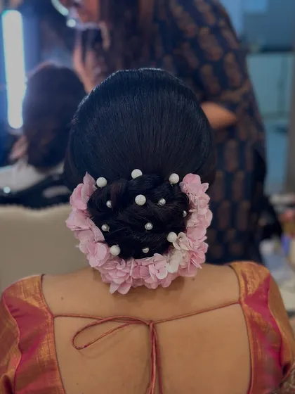 A full back view of the textured bun with pink flowers and pearls, showcasing a romantic and detailed bridal updo.