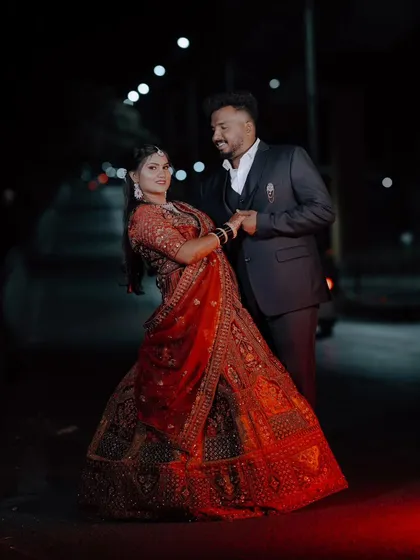 A romantic dance pose on a street at night. The bride's red lehenga swirls around her, creating a beautiful, dynamic shot.