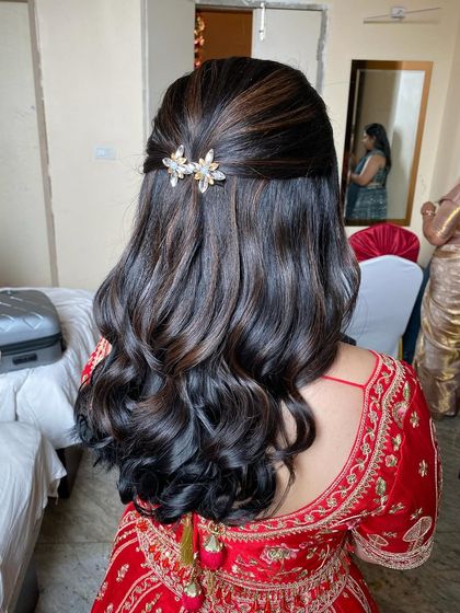 A beautiful half-up hairstyle with soft waves and subtle highlights, accented with a pair of delicate floral clips.