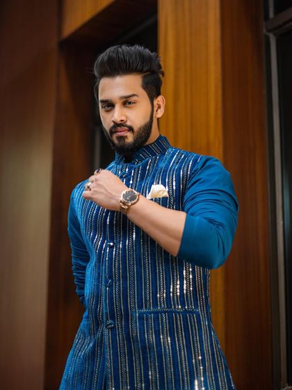 The client exudes confidence in his vibrant blue Indo-Western outfit, a perfect fusion of modern style and festive flair.
