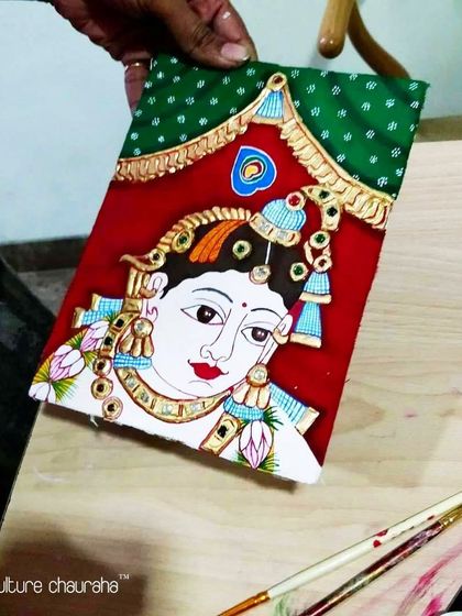 A student working on a traditional Tanjore painting, a classical South Indian art form known for its gold foil and gemstone embellishments.