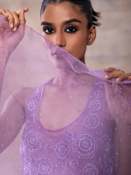 A mysterious and artistic shot with a sheer lavender veil. The makeup is focused on a dark, intense eye, creating a captivating look that is perfect for a bride who wants to make a high-fashion statement.