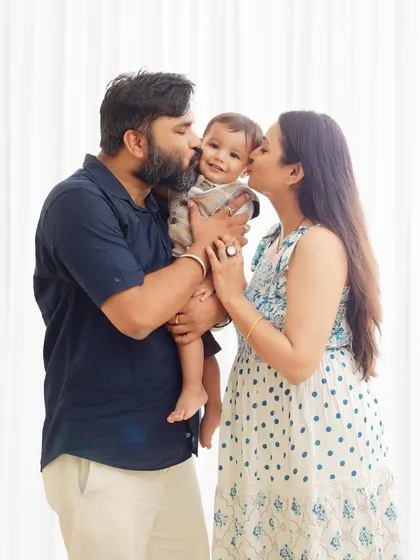 A pre birthday photoshoot is a wonderful way to capture the whole family. Here, loving parents give their smiling baby a kiss in our bright and airy indoor studio.