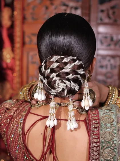 Our hair expert, Ritu Yadav, created this intricate bridal bun. Notice the detailed weaving and the elegant placement of shell accessories, making it a unique and sophisticated choice for a wedding day hairstyle.