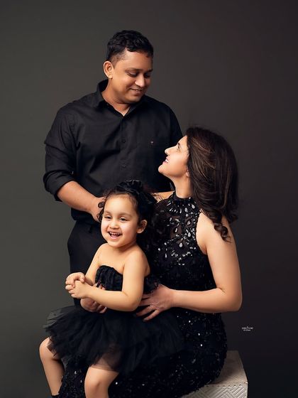 A happy family of three. The little girl's big smile is the centerpiece of this joyful family portrait, surrounded by her loving parents.