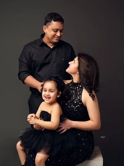 A happy family of three. The little girl's big smile is the centerpiece of this joyful family portrait, surrounded by her loving parents.