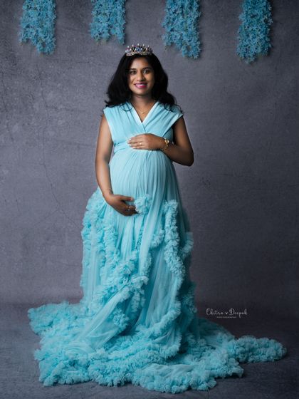 A princess moment. This mom-to-be wears a tiara with a beautiful sky-blue gown, creating a sweet and regal pregnancy portrait.