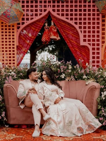 A wide shot of the couple seated on a sofa against a vibrant, Rajasthani-themed decor for their Sangeet.