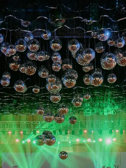 The disco ball ceiling illuminated by green stage lights, creating a vibrant, party-ready atmosphere.