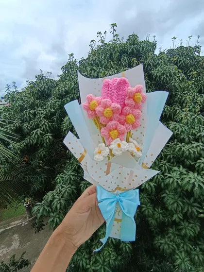 A sweet bouquet with a tulip and daisies, wrapped with a blue ribbon.